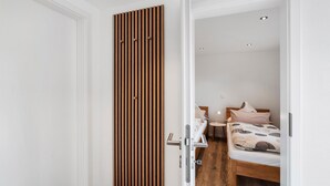 Un dormitorio con un separador de listones de madera, una cama con colcha estampada y una mesita de noche con lámpara.