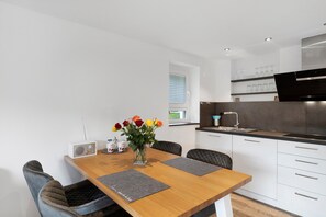 A modern kitchen with white cabinets, a black countertop, and a built-in oven.