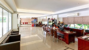 Un hall d’hôtel spacieux avec un comptoir d’accueil, un coin salon et une cuisine en arrière-plan.