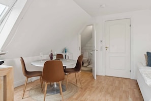 A modern, well-lit room with a dining table, chairs, and a white door.