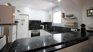 Een moderne keuken met witte kasten, een zwart aanrecht en een ingebouwde oven.