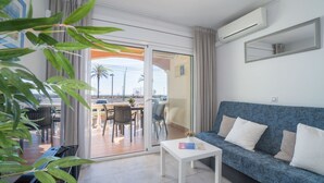 A modern living room with a sofa, a coffee table, and a sliding glass door leading to an outdoor patio. - Apartment in Empuriabrava with Sea Views (Empuriabrava)