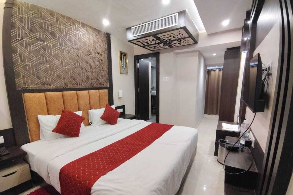 A hotel room with a large bed, a television, and a minibar.