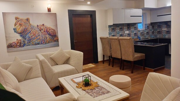 A modern living room with a sofa set, a coffee table with decorative items, and a painting of a dog on the wall. - BRIKitt Majestic Nirvana 2BHK Suite- Mukteshwar (South Gola Range)