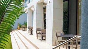 A modern outdoor seating area with tables and chairs, a staircase leading to an entrance, and a potted plant on the left. - Africa's Touch & Leisure (Kigali)