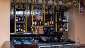 A bar area with shelves of wine bottles, a counter with glasses, and hanging plants. - Africa's Touch & Leisure (Kigali)