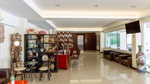 Un vestíbulo amplio con mostrador de recepción, zona de estar y un jarrón decorativo.