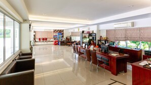 Una oficina amplia y luminosa con recepción, varias estaciones de trabajo y un comedor con sillas y mesas.