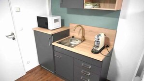 Cocina pequeña con un lavamanos, microondas y cafetera en la encimera.