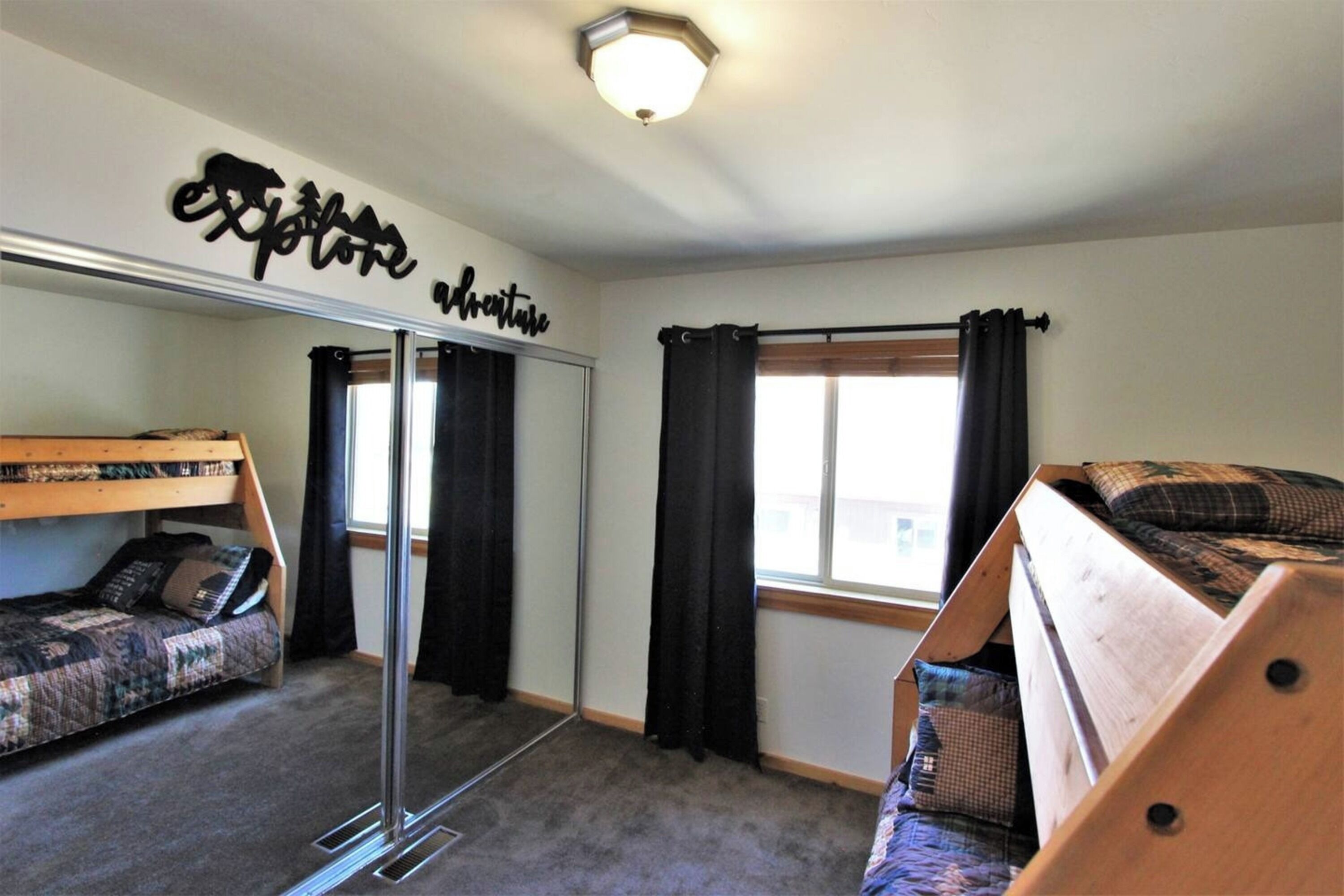 A room with a bunk bed, a pull-out desk, and a mirror.
