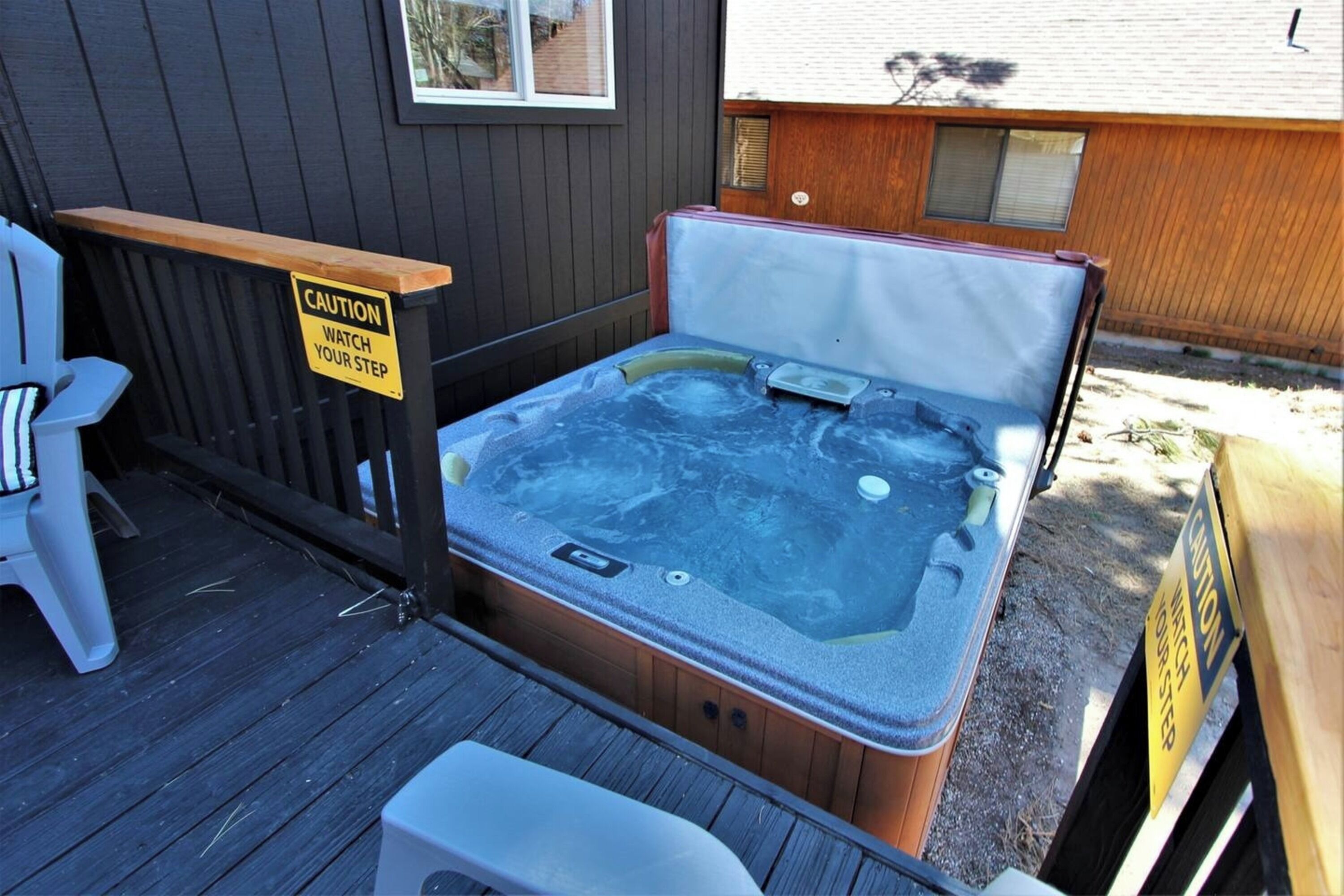 A hot tub on a wooden deck with caution signs.