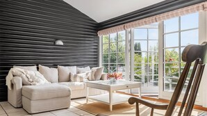 A modern living room with a black wall, a white sofa, a coffee table, and a wooden chair. - Cozy home in Dronningmølle with WiFi (Dronningmølle)