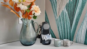 A room with a vase of flowers, a coffee maker, and two mugs on a table. - Elegant and cosy flat in Milan, closed to Fashion District, Navigli and Duomo (Milan)