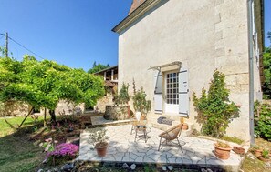 A house with a stone patio, two wicker chairs, and a small table. - Manoir de la Boissière (Jaure)