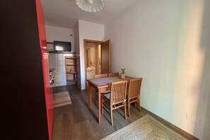 Una cocina compacta con zona de comedor, muebles de madera y una planta en maceta.