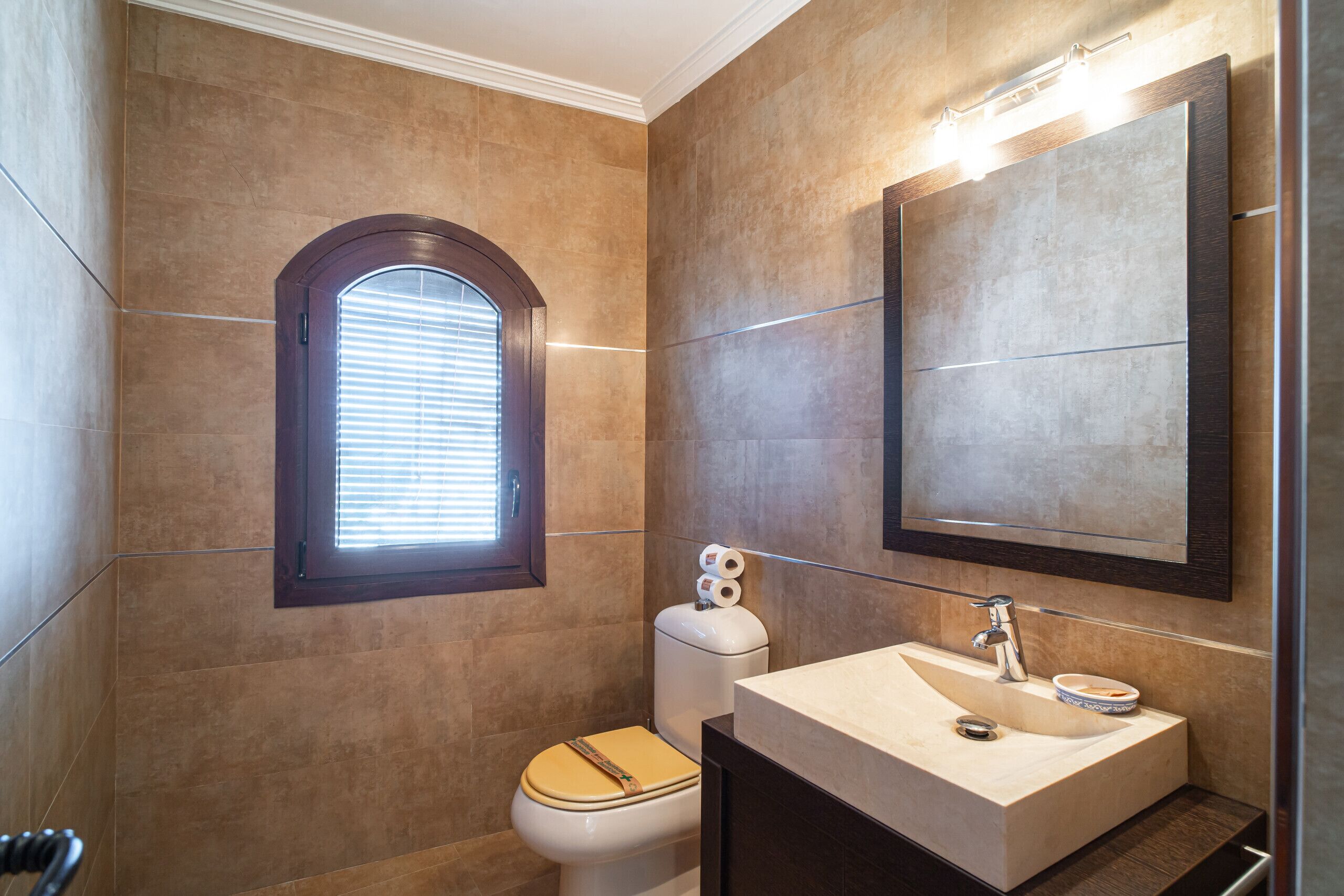 A bathroom with a toilet, sink, and window.