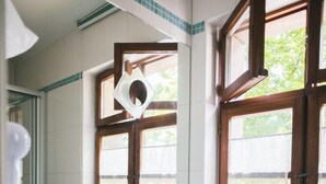 Een badkamer met een wastafel, spiegel en raam met houten kozijnen.