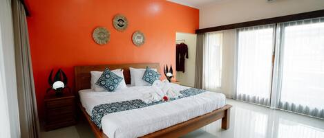 Un dormitorio amplio con una cama grande, una mesita de noche de madera y una mesilla auxiliar.