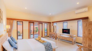 Ampia camera d'albergo con un letto grande, una scrivania in legno, una televisione e vista sull'esterno.