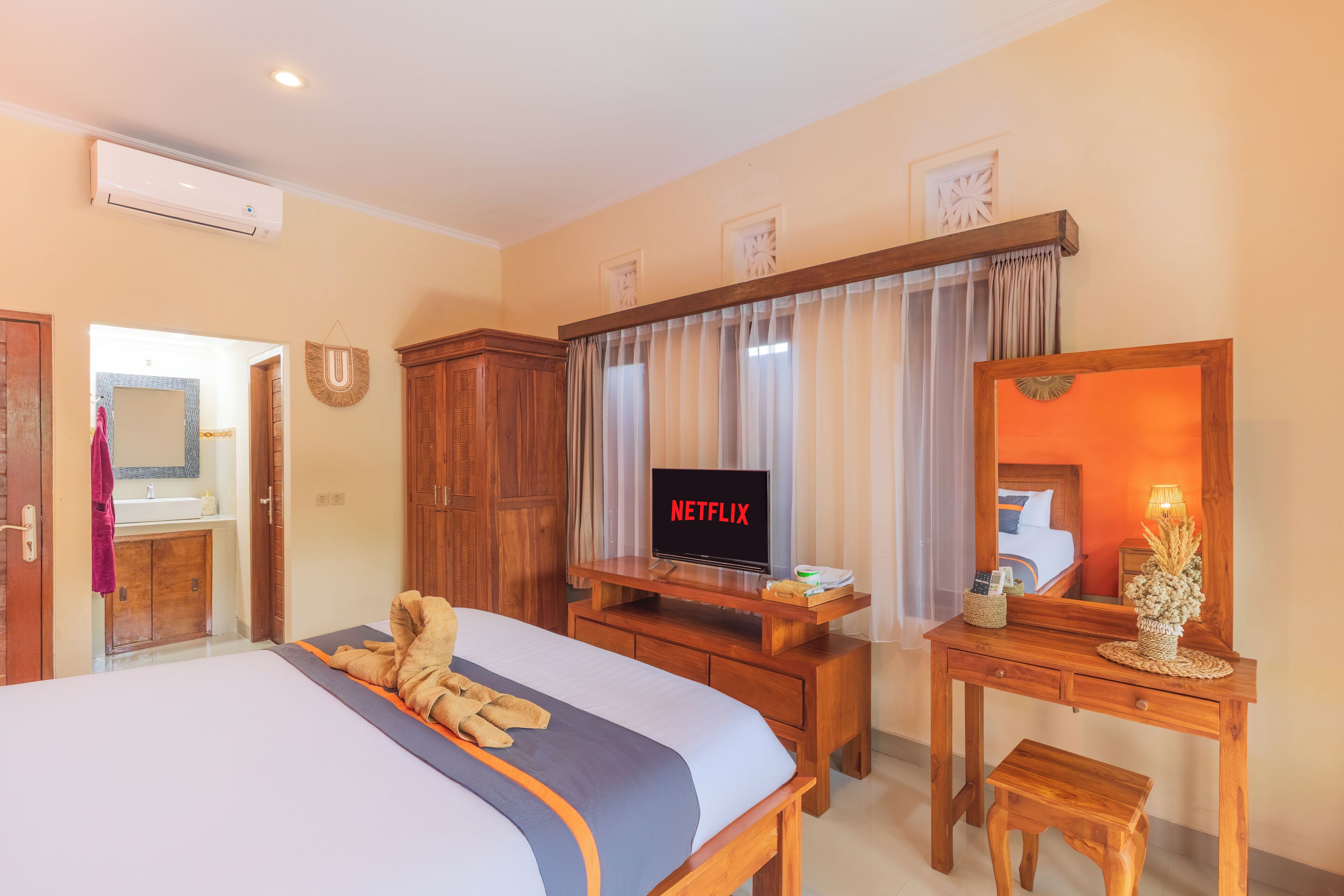 A hotel room with a bed, wooden desk, TV, and a mirror.