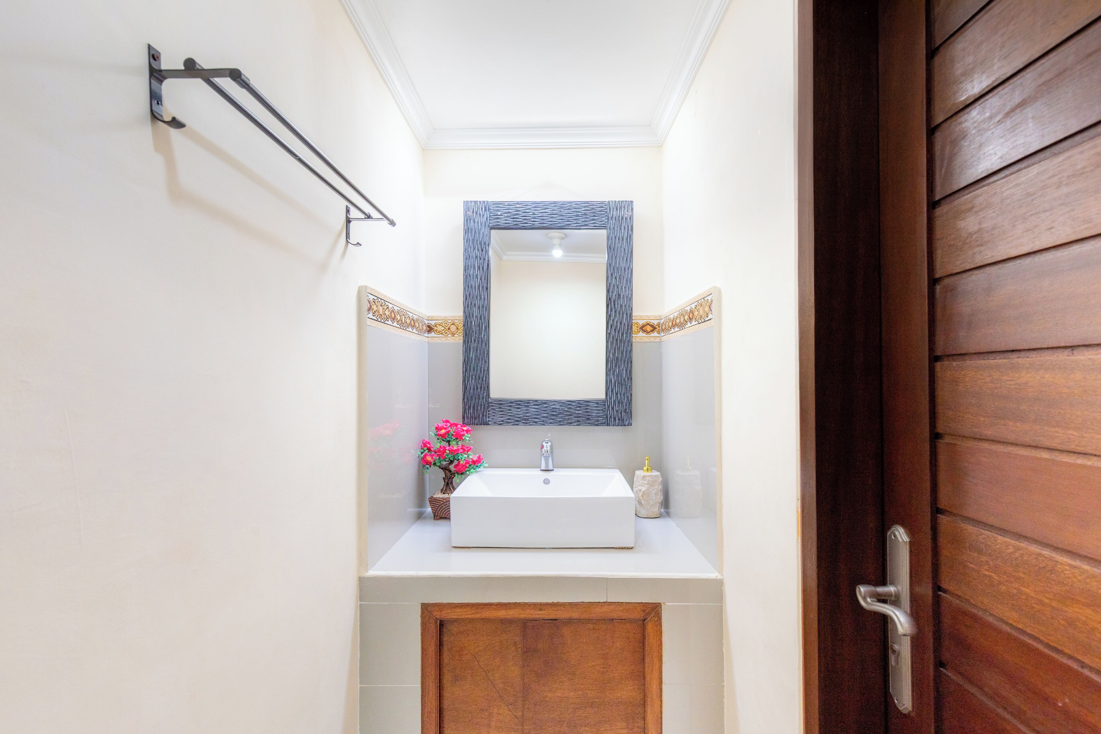 A bathroom with a white sink, a mirror, and a wooden door.