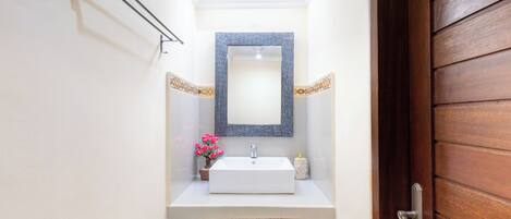 A bathroom with a white sink, a mirror, and a wooden door.