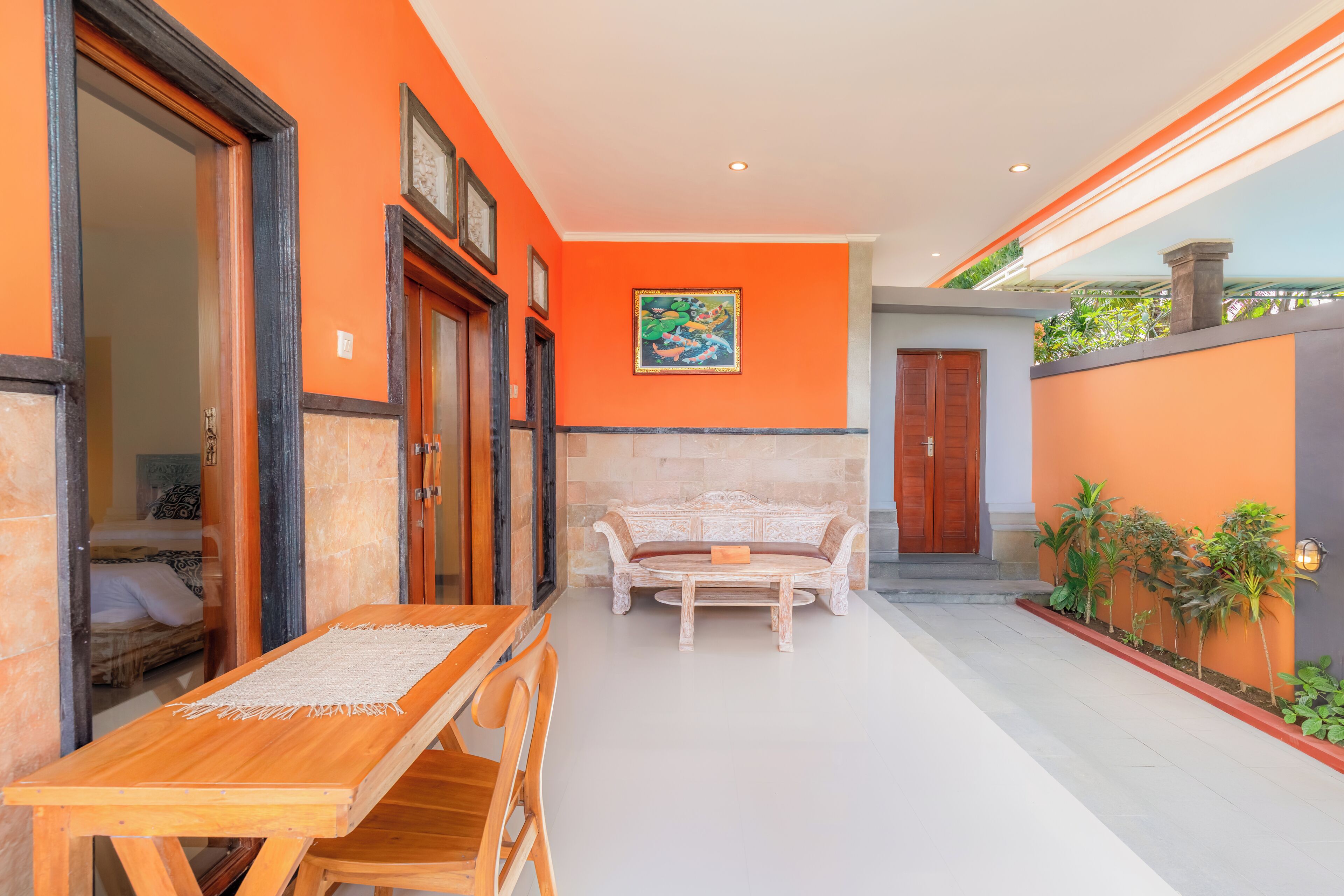 Una habitación con una mesa y sillas de madera, un banco acolchado y una puerta que da a un dormitorio.