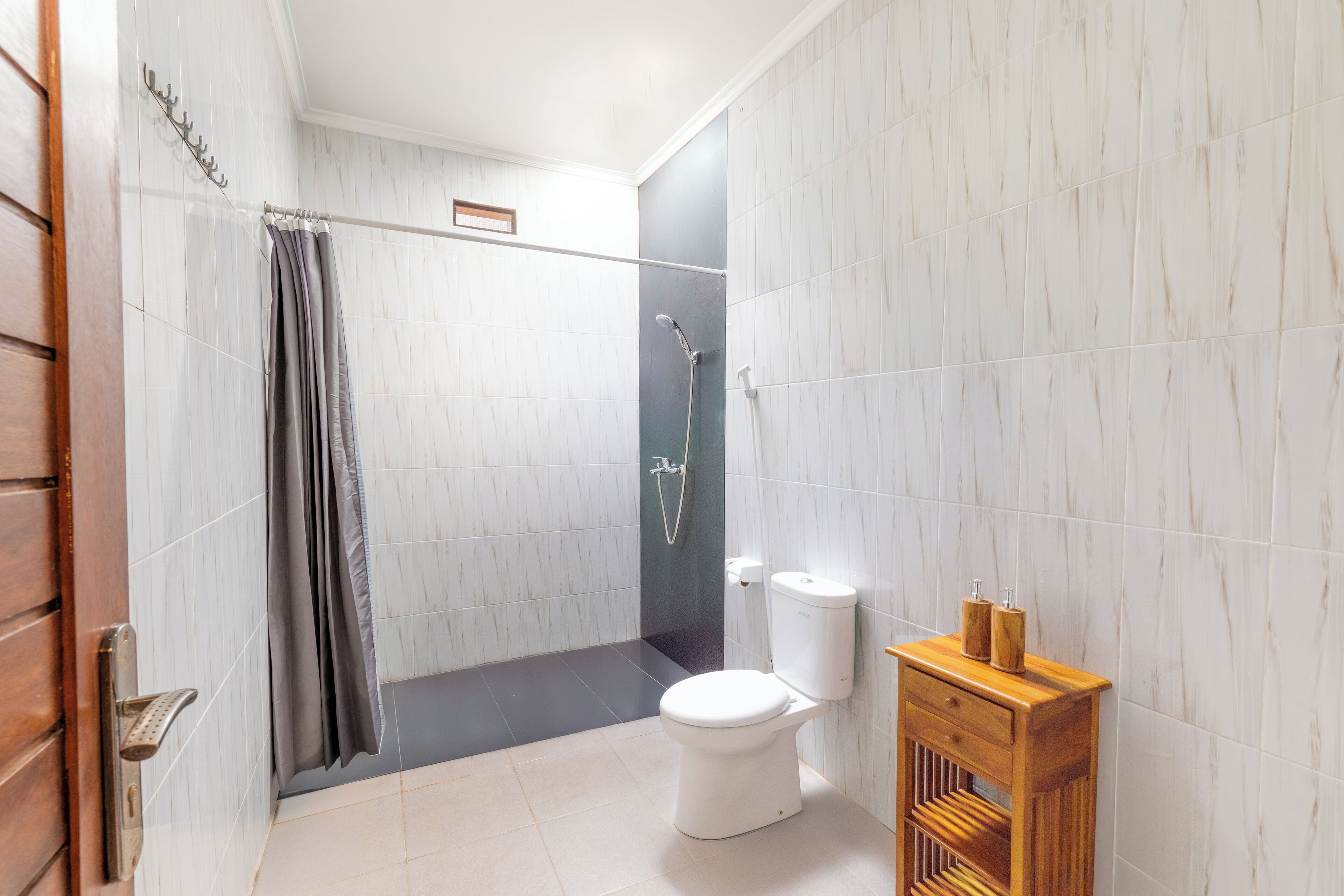 A bathroom with a shower, toilet, and wooden vanity.