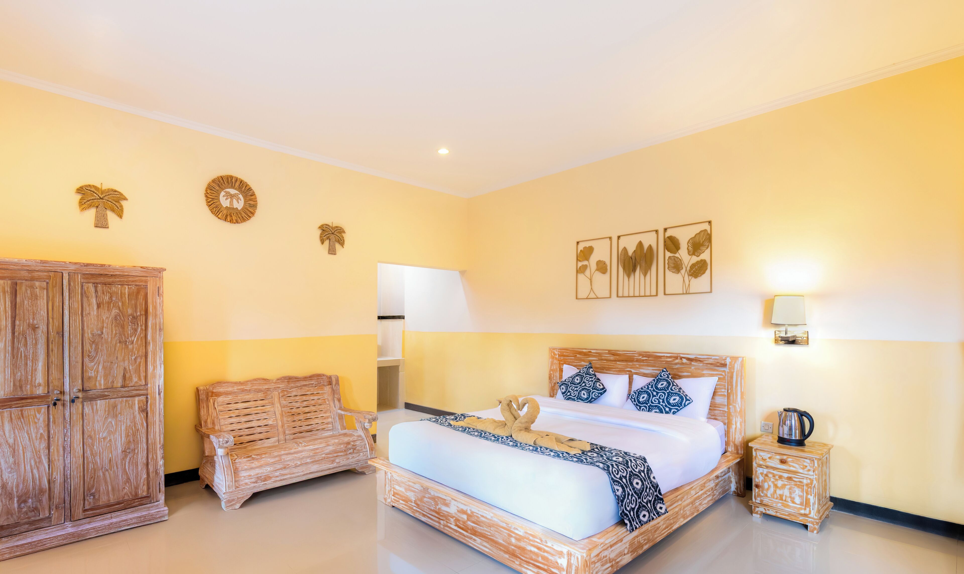 Una habitación de hotel con una cama grande, un banco de madera, un armario y decoración en la pared.