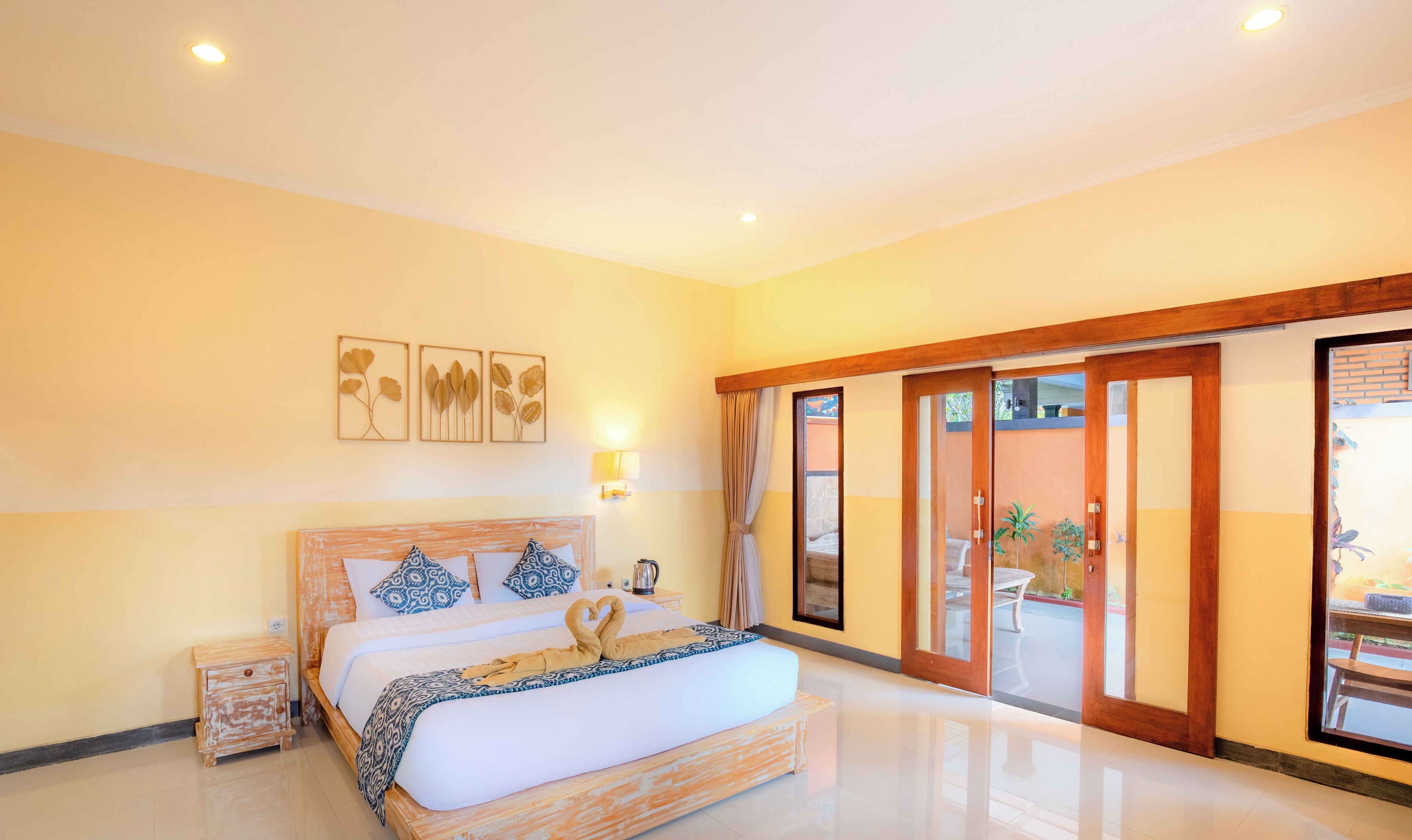 A bedroom with a large bed, a wooden headboard, a nightstand, and a wall-mounted light.