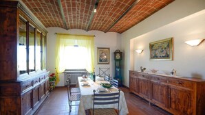 A dining room with a long wooden table, chairs, and a clock on the wall.