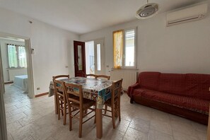 A dining area with a table and chairs, a red sofa, and a window with curtains.