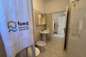 A bathroom with a toilet, bidet, sink, and mirror.