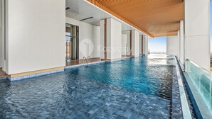 A modern indoor swimming pool with a wooden ceiling and a clear view of the sky. - Branca by Kozystay - Alam Sutera (Tangerang)