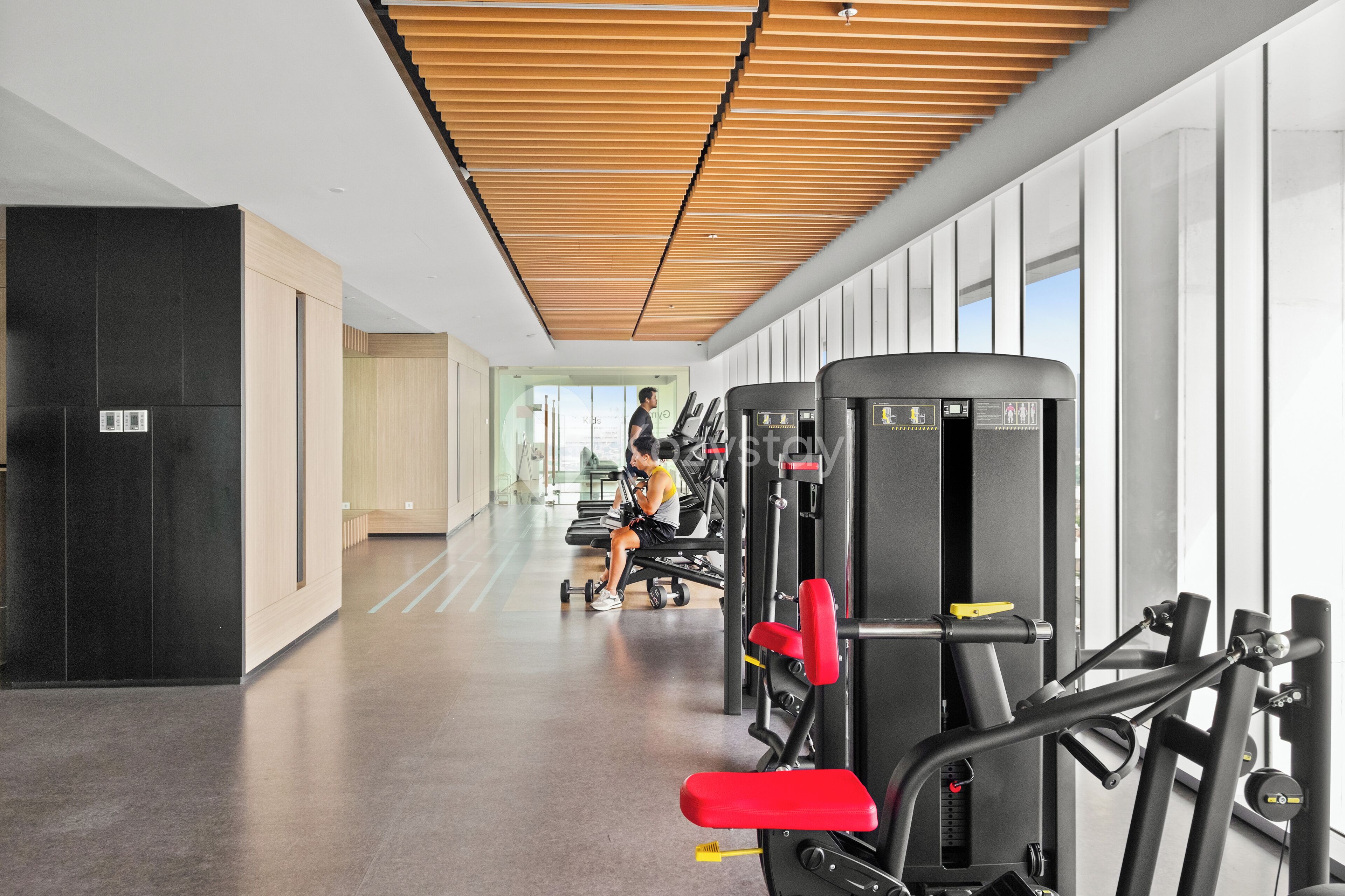Un gimnasio con equipamiento de ejercicio, una persona usando una máquina y un diseño de interiores moderno.