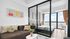 A modern hotel room with a large bed, a sofa, and a balcony with a city view. - Branca by Kozystay - Alam Sutera (Tangerang)