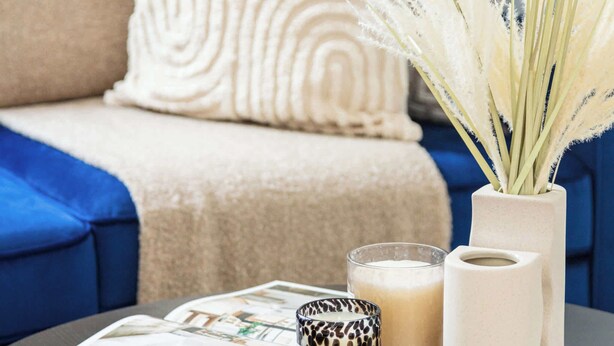 A round table with a magazine, a candle, and a vase with dried flowers. - Charming 1BR in the Heart of Soho and Fitzrovia (London)
