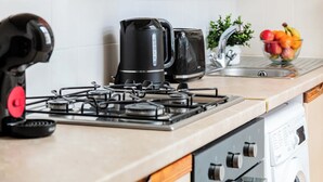 A kitchen with a gas stove, a coffee maker, a toaster, and a sink with a fruit bowl. - Charming 1BR in the Heart of Soho and Fitzrovia (London)