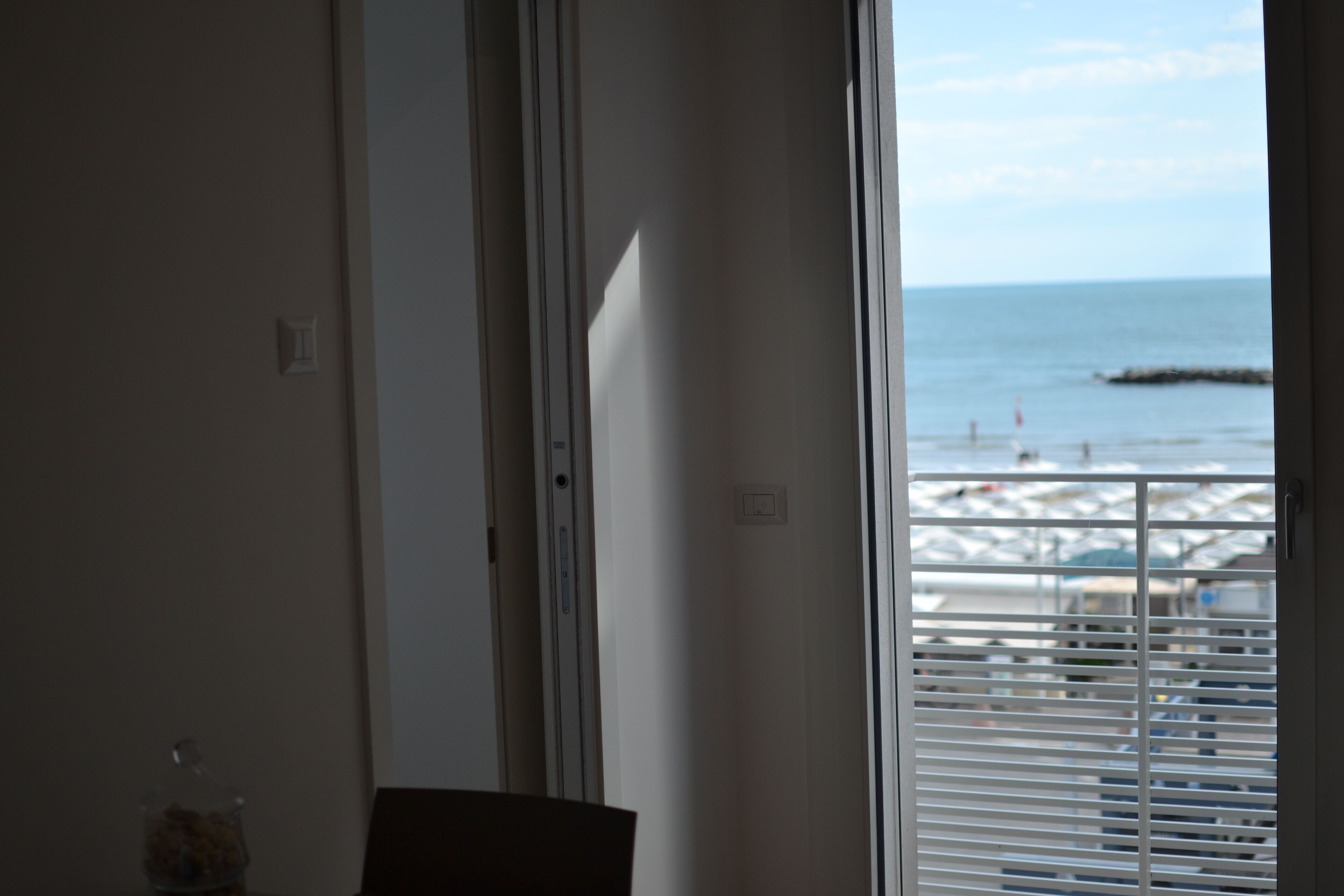 Ein Zimmer mit Meerblick durch ein Fenster mit Jalousien.