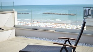 Un balcón con vista a la playa, una silla y una barandilla.