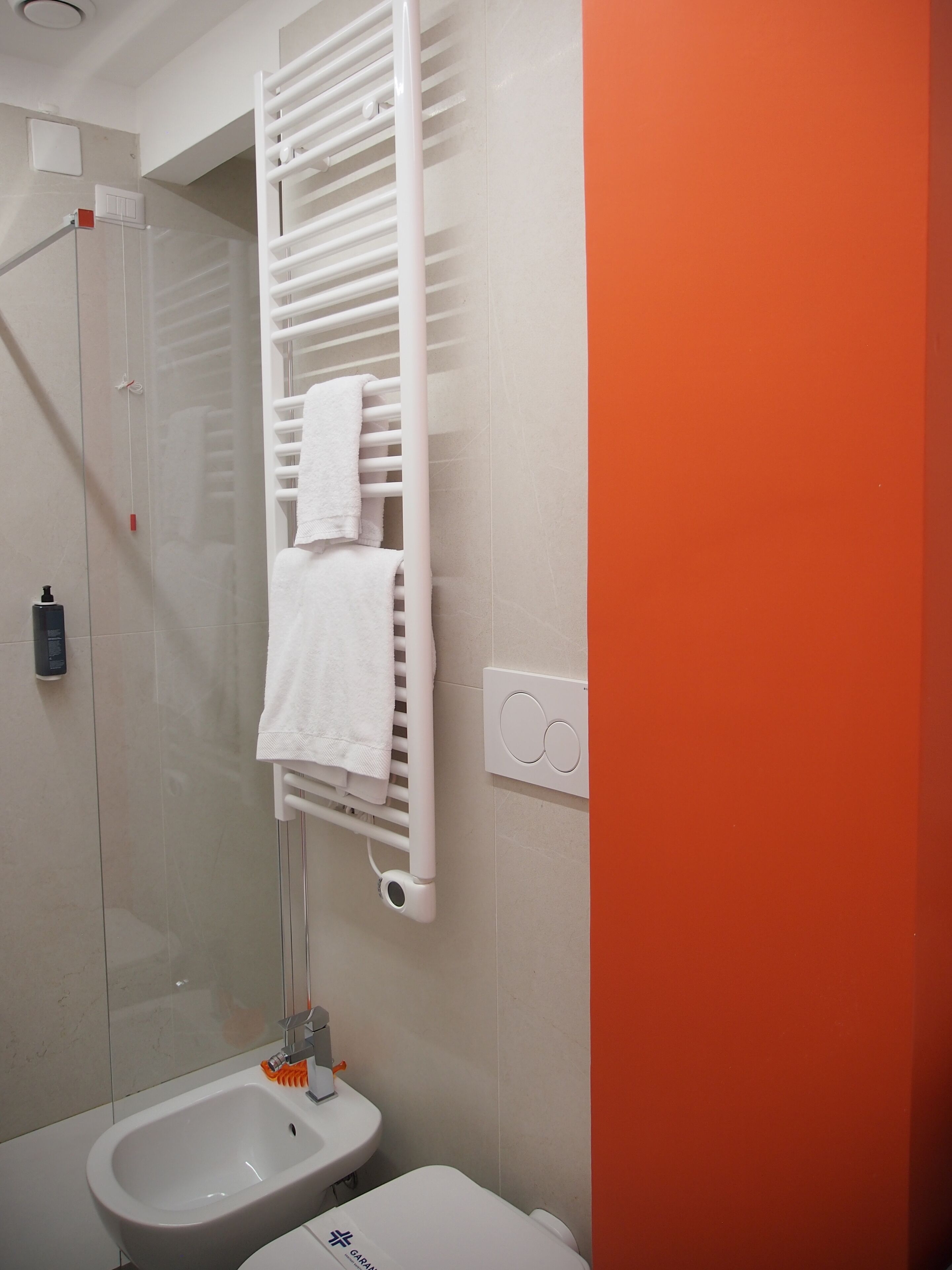 Un baño con una bañera blanca, un inodoro blanco y un perchero blanco con toallas.
