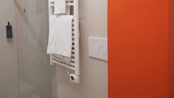 Un baño con una bañera blanca, un inodoro blanco y un perchero blanco con toallas.