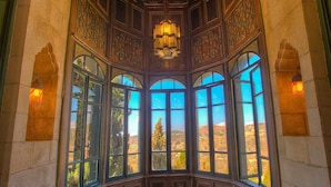 Una habitación con vistas amplias, ventanas arqueadas, piso estampado y un candelabro.