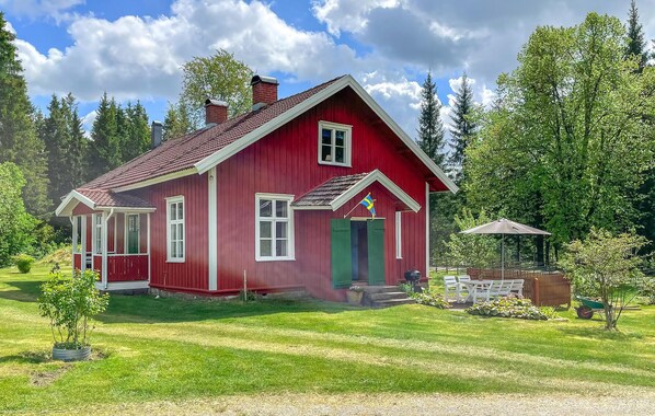 A red wooden house with a sloped roof, a front porch, and a flag. - Beautiful home in Grimsås (Grimsås)