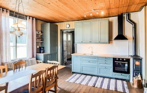 A cozy kitchen with light blue cabinets, a wooden dining table, and a stove.