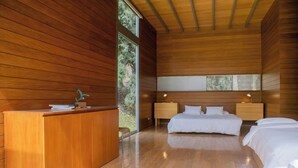 Un dormitorio moderno con paneles de madera, un escritorio, dos camas y un ventanal grande.
