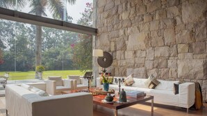 Una sala de estar moderna con una pared de piedra, un ventanal y vistas a un jardín.