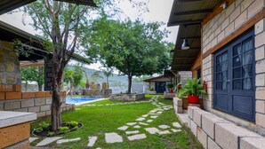 A courtyard with a stone pathway, a small pool, and a building with a dark door. - Quinta Allende |Alberca, Bar, Palapa con asador, Futbol, Voleibol, Juegos Infantiles (Los Adobes)