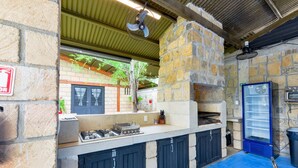 An outdoor kitchen area with a gas stove, a pizza oven, and a blue refrigerator. - Quinta Allende |Alberca, Bar, Palapa con asador, Futbol, Voleibol, Juegos Infantiles (Los Adobes)