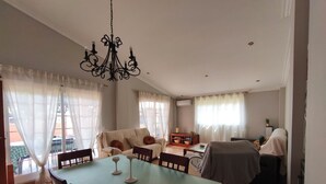 A dining area with a table and chairs, a sofa, and a chandelier. - Villa Pepita (VC)